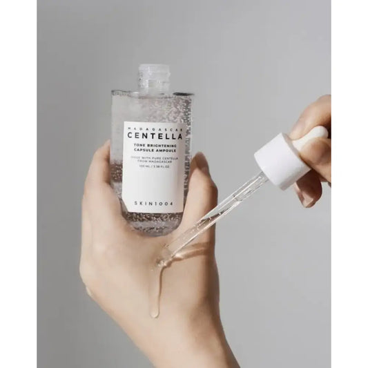 Clear glass dropper bottle with white label and shimmering liquid from acne fighter set for acne treatment