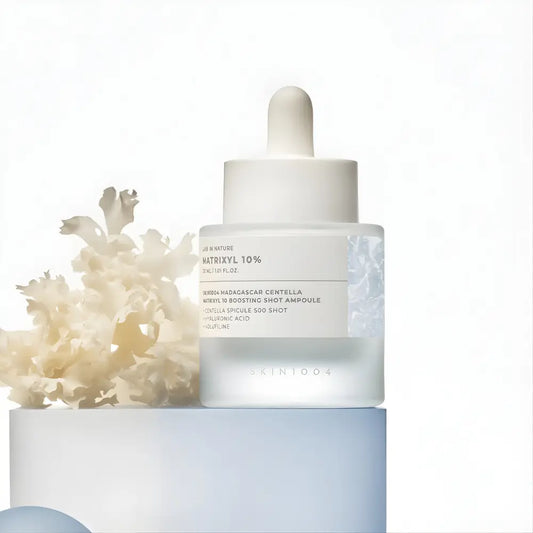 A sleek transparent glass bottle with white dropper cap containing skin1004 madagascar centella matrixyl boosting shot ampoule