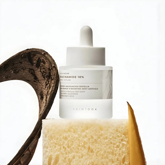 A sleek transparent glass bottle with a white dropper cap containing skin1004 madagascar centella niacinamide boosting shot ampoule