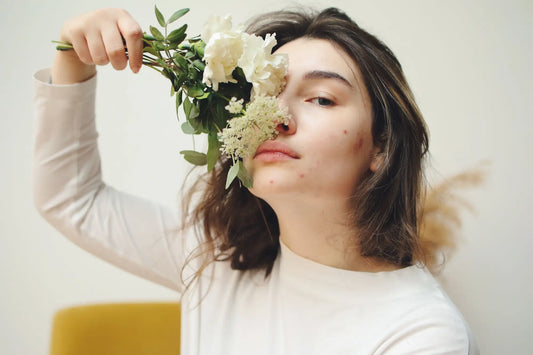 A delicate bouquet of white flowers with green foliage held by hand illustrating post-inflammatory hyperpigmentation care.