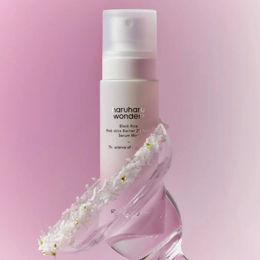 A sleek white spray bottle of haruharu wonder black rice probiotics barrier 2% nad serum mist with white flowers at base
