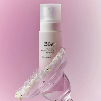 A sleek white spray bottle of haruharu wonder black rice probiotics barrier 2% nad serum mist with white flowers