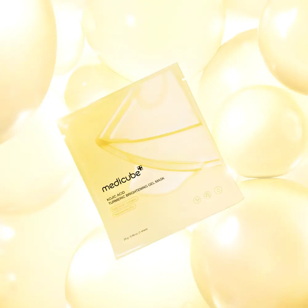 A pale yellow translucent pouch of medicube koji acid turmeric gel mask for brightening and uneven tone correction