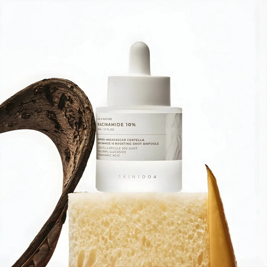 A sleek transparent glass bottle with white dropper cap containing skin1004 madagascar centella niacinamide boosting shot ampoule