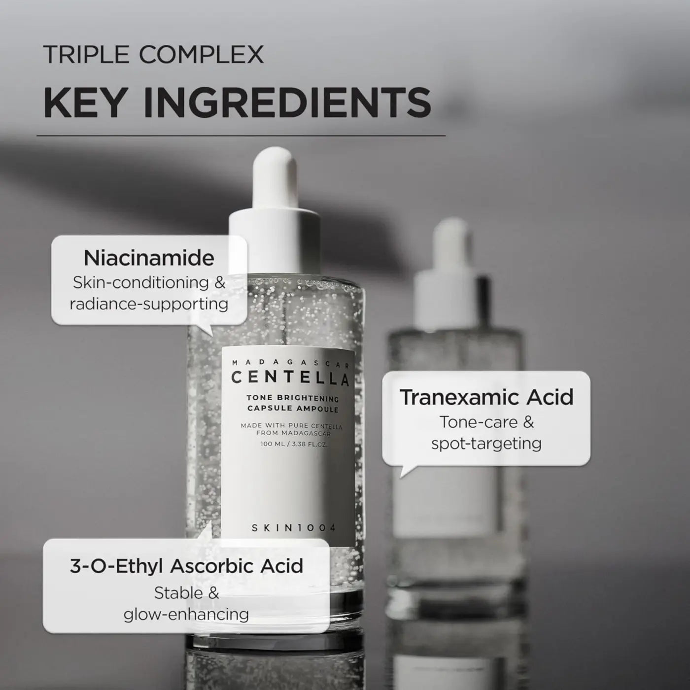 Clear glass bottle with white dropper cap labeled madagascar centella tone brightening capsule ampoule by skin1004