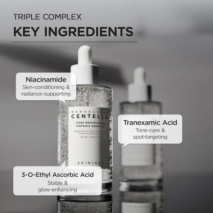 Clear glass bottle with white dropper cap labeled madagascar centella tone brightening capsule ampoule by skin1004