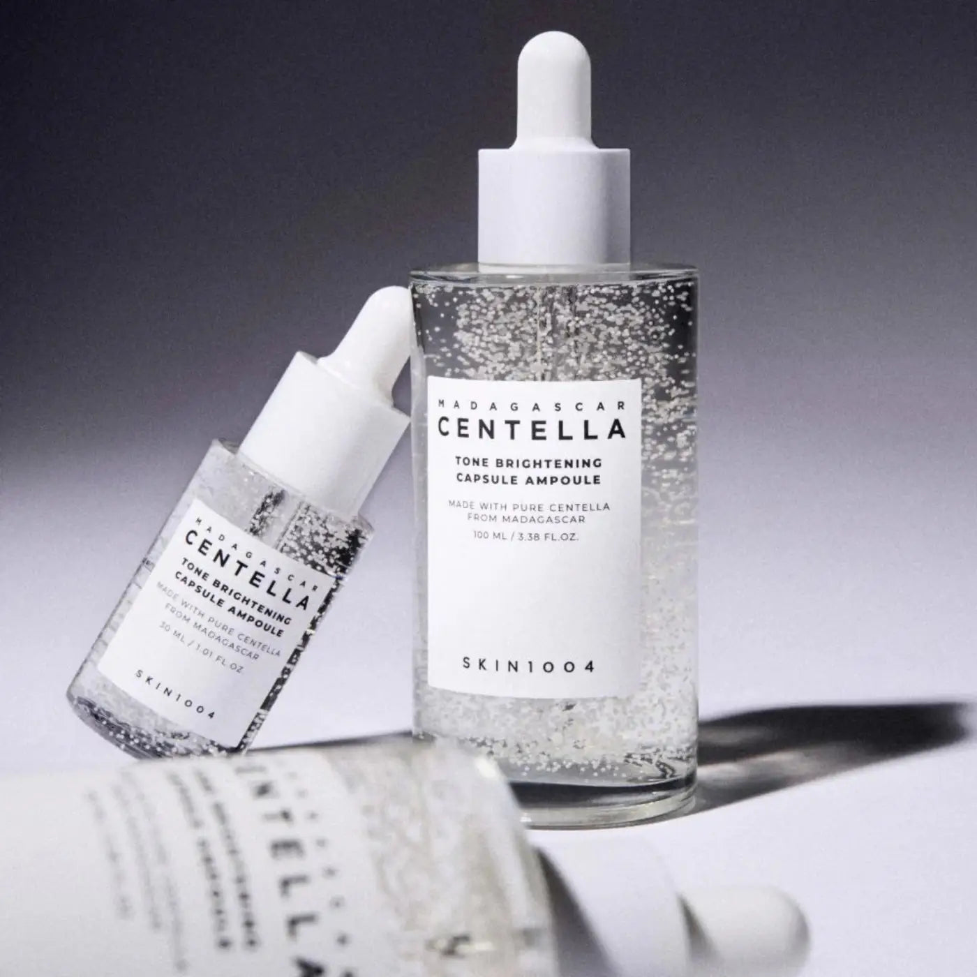 Clear glass bottle with white dropper cap containing sparkling transparent madagascar centella brightening capsule ampoule