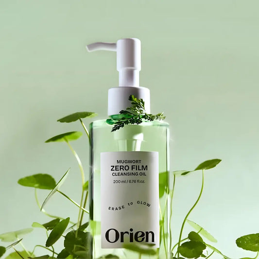 Clear glass bottle of Mugwort Zero Film Cleansing Oil 200ml with white pump and green plant sprigs for zero film cleansing