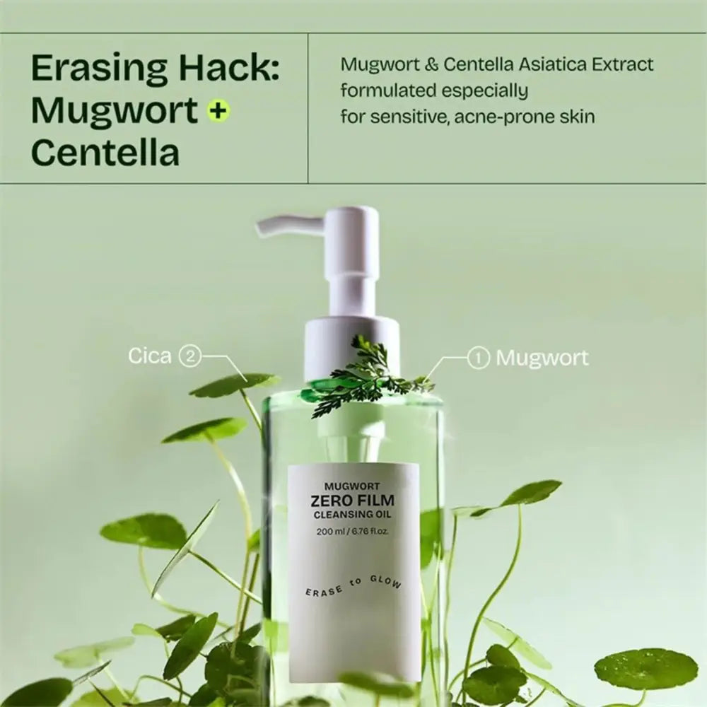 Clear glass bottle of mugwort zero film cleansing oil with white pump and fresh green mugwort leaves visible