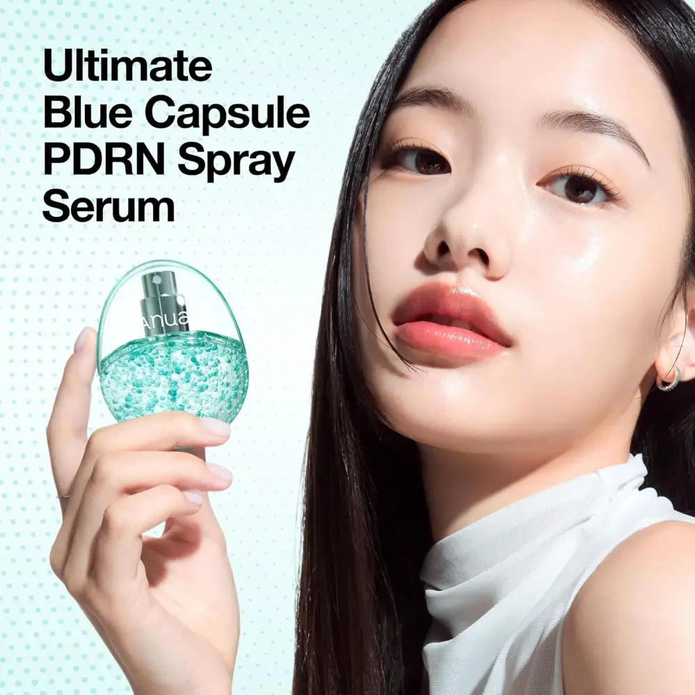 A translucent teal glass bottle of anua pdrn collagen glow facial serum spray with a silver nozzle and blue capsules