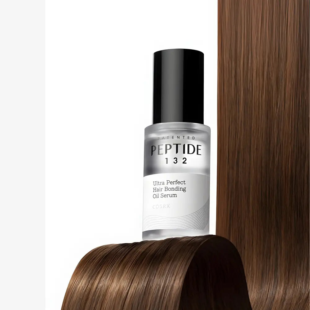 A sleek transparent glass bottle with black cap and minimalist white label for cosrx peptide 132 ultra perfect hair bonding oil serum