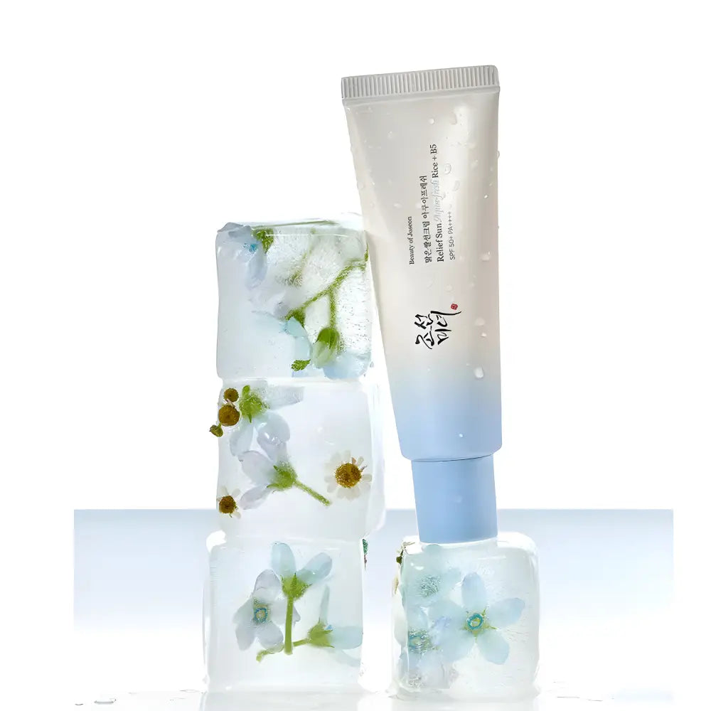 A translucent blue gradient tube of beauty of joseon relief sun aqua-fresh rice sunscreen spf50 pa++++ displayed with ice cubes containing frozen flowers highlighting rice seed water and k-beauty south africa