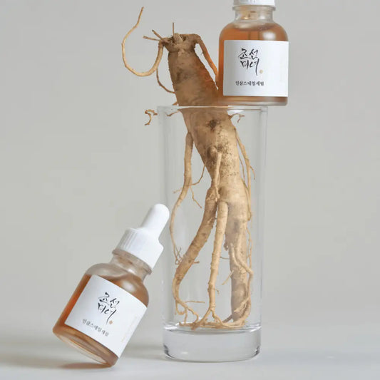 A clear glass bottle of revive serum with amber snail mucin and ginseng root water and white dropper cap