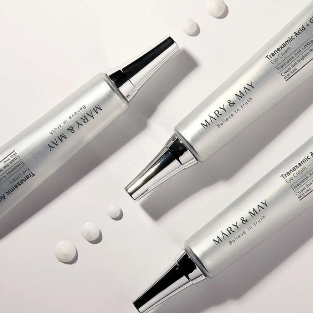 Three sleek silver tubes of mary & may tranexamic acid glutathione eye cream with black caps and metallic accents 30ml