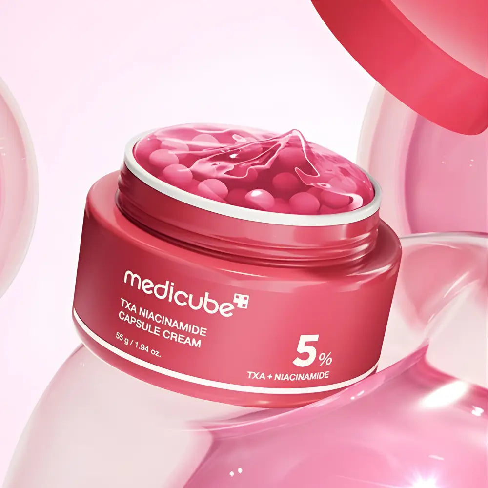 A vibrant pink medicube txa niacinamide capsule cream jar with translucent capsules for improving skin tone