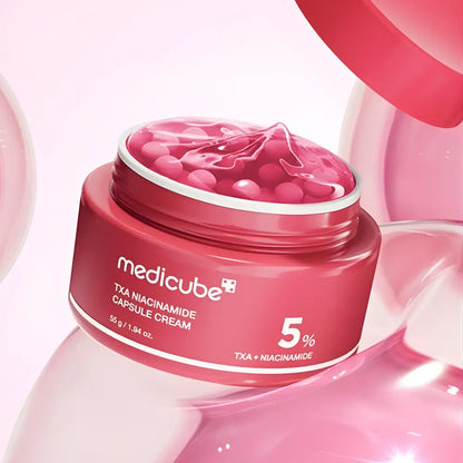 A vibrant pink medicube txa niacinamide capsule cream jar with translucent capsules for improving skin tone
