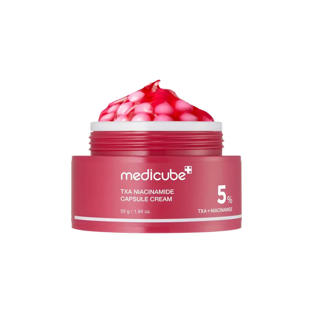 A vibrant red jar of medicube txa niacinamide capsule cream 55g with pinkish red gel capsules inside for skin tone