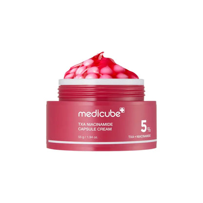 A vibrant red jar of medicube txa niacinamide capsule cream 55g with pinkish red gel capsules inside for skin tone
